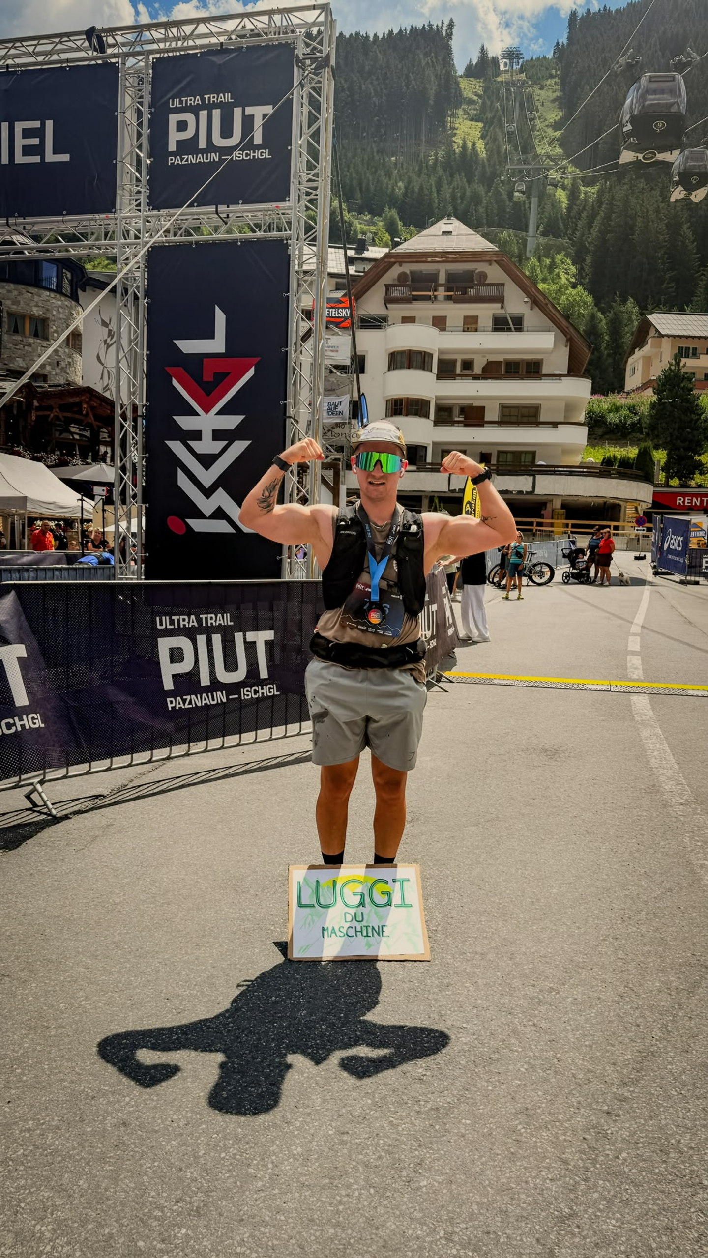 Lukas Ludl mit Medaille und erhobenen Armen im Ziel eines Trailrennens.