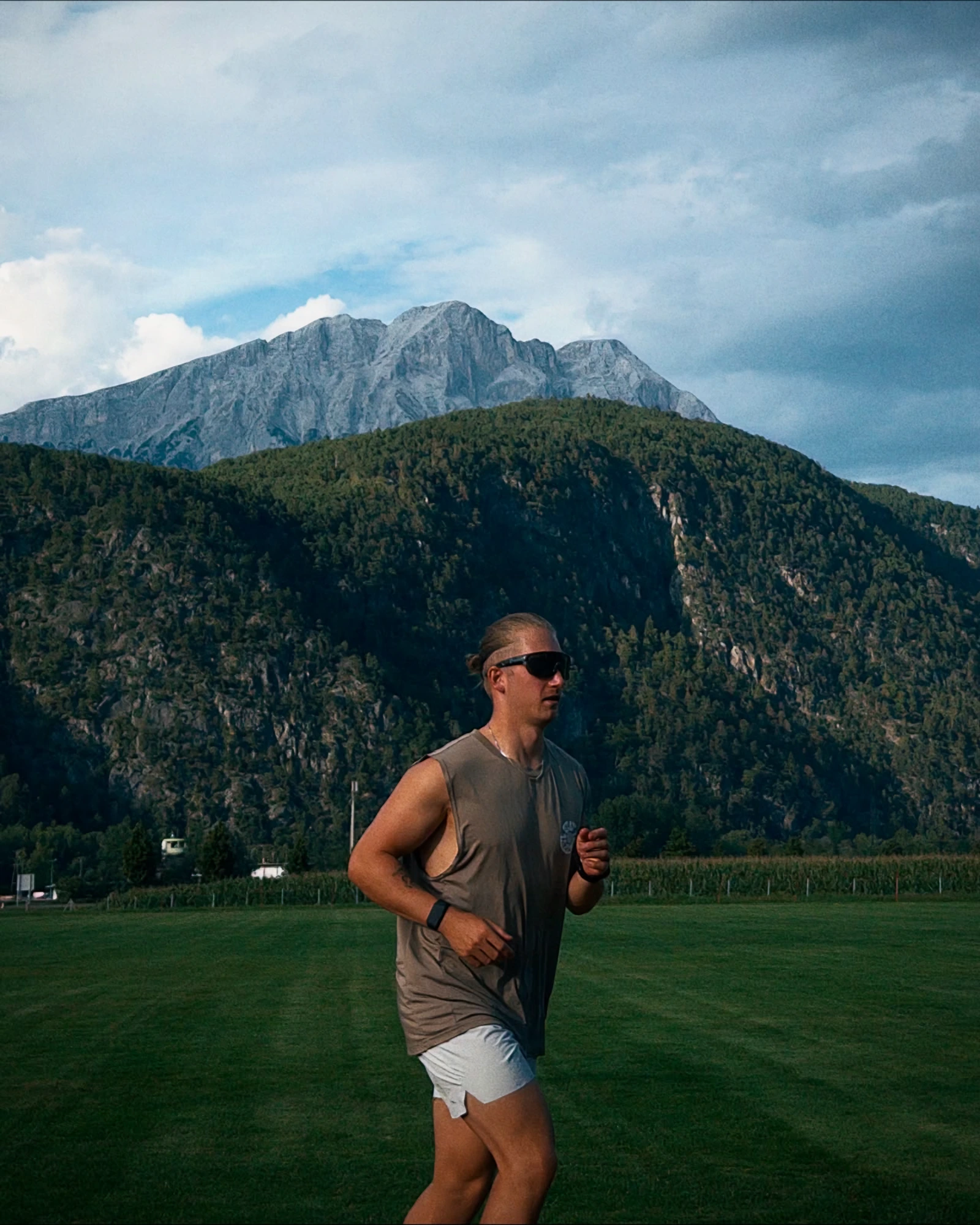 Lukas Ludl beim Lauftraining auf einer Wiese mit Bergen im Hintergrund.