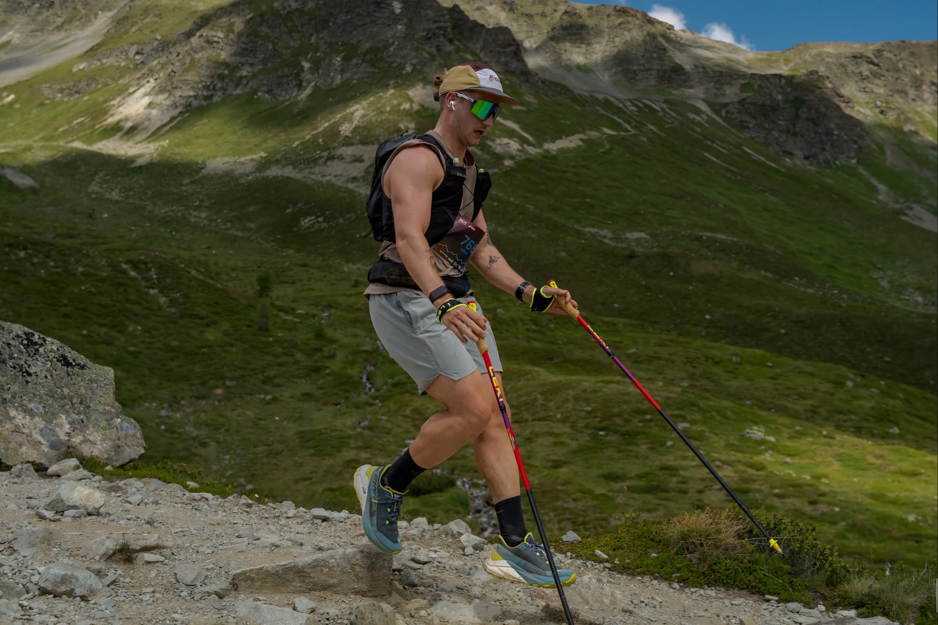 Lukas Ludl mit Stöcken auf einem felsigen Bergtrail, von der Seite fotografiert.